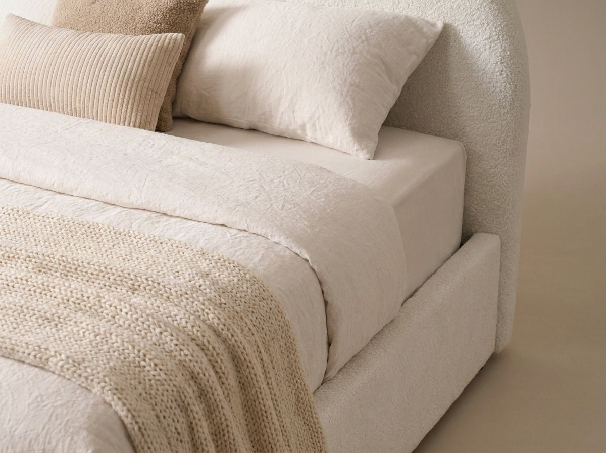Close-up of the Velets Flora ivory boucle headboard and upholstered side panel with knit throw.